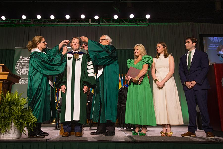 Northwest Regents Mel Tjeerdsma 和 Roxanna Swaney placed the University's chain of office on Dr. 兰斯·塔图姆的肩膀，他的家人在一旁看着. (Photo by Lauren Adams/<a href='http://letzoo.fc-daudenzell.com'>网上赌博网站十大排行</a>)